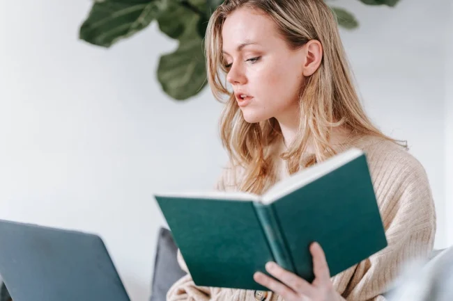 Serious woman with notebook checking and surfing laptop